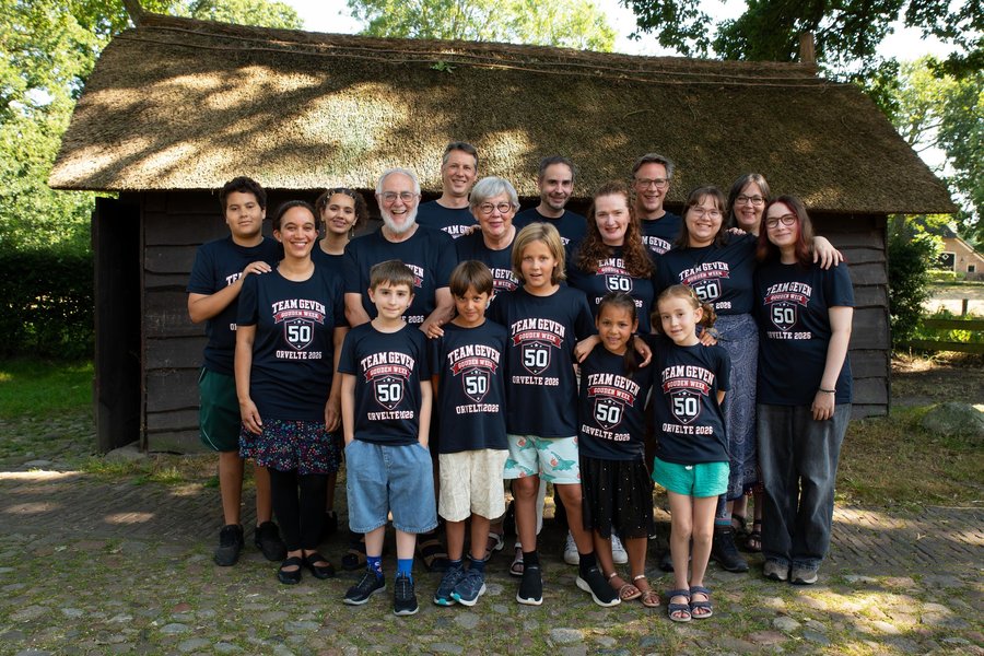 Alle zeventien familieleden in het donkerblauwe Team Geven-shirt, poserend voor de rieten schuur bij de fotoshoot