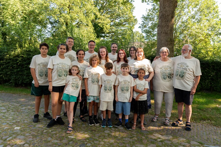 Alle zeventien familieleden in het crèmekleurige Stamboom-shirt, in de schaduw van de grote boom