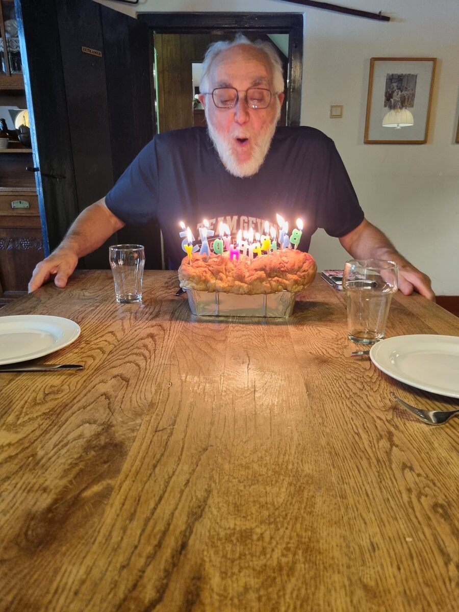 Albert blaast de kaarsjes uit op een grote taart aan de houten tafel