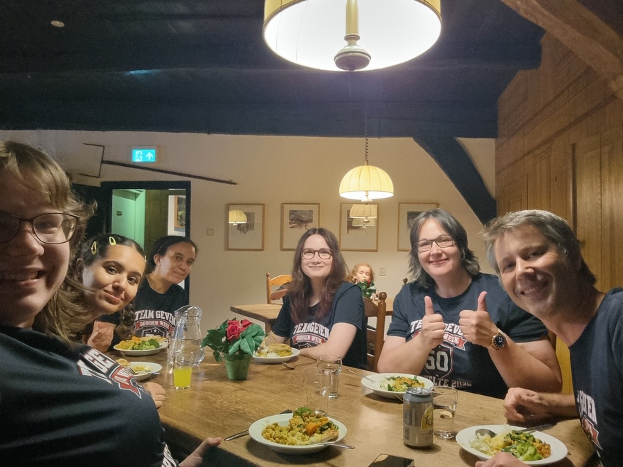 Familieleden in het donkerblauwe Team Geven-shirt aan een tafel in het restaurant